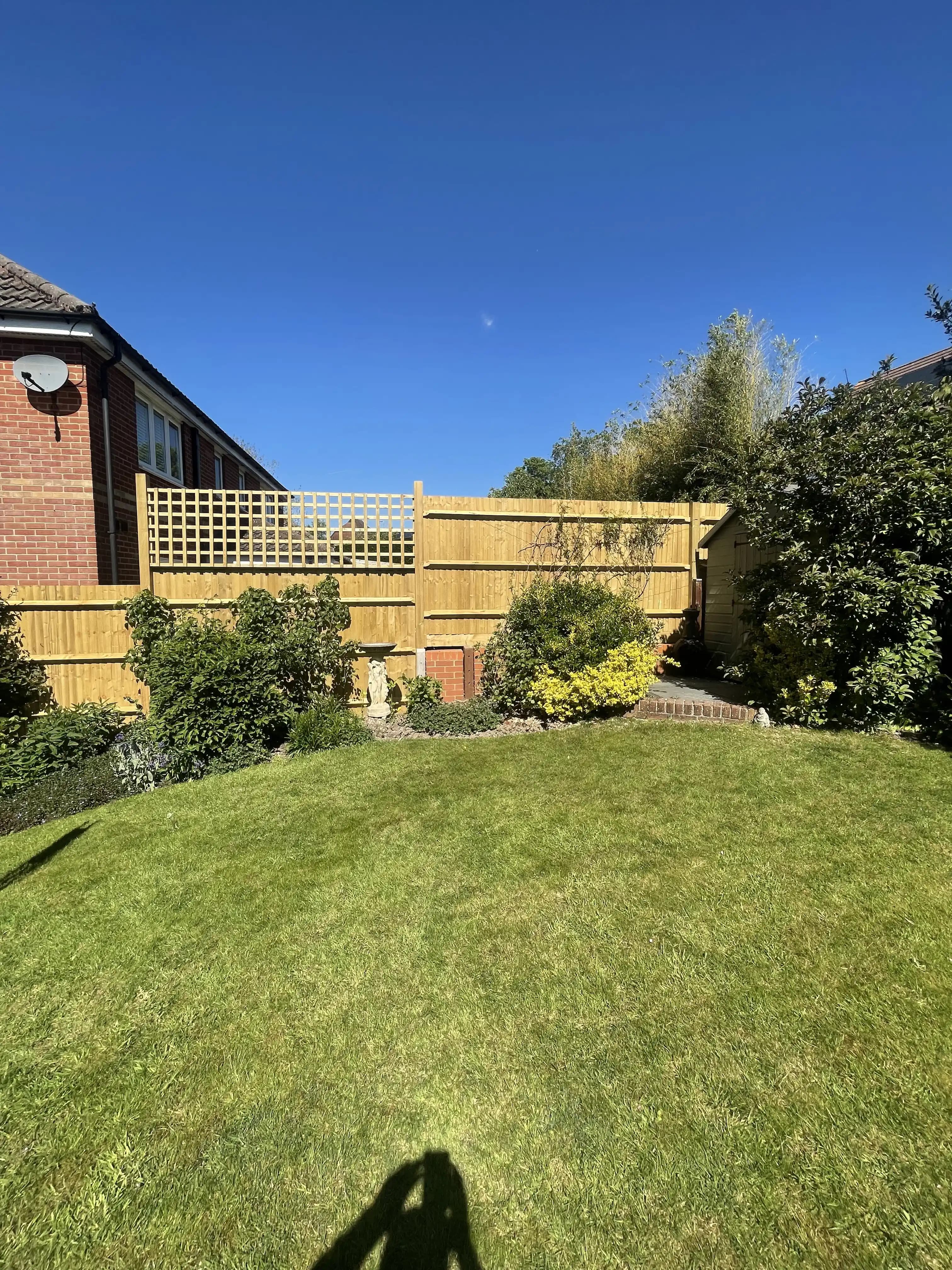 Closeboard boundary fence around a neat sunny garden lawn