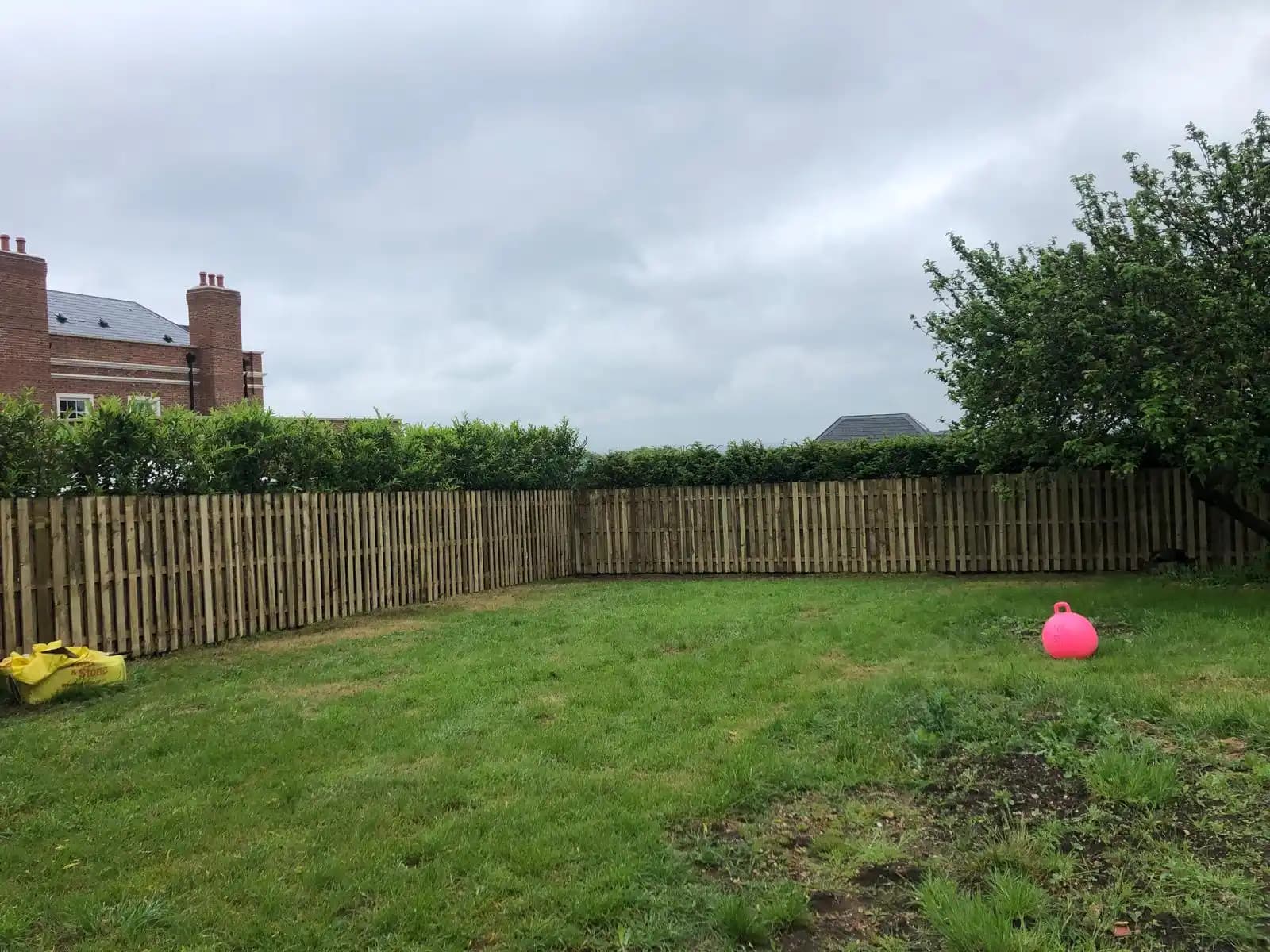 Timber boundary fence across the back of a garden lawn