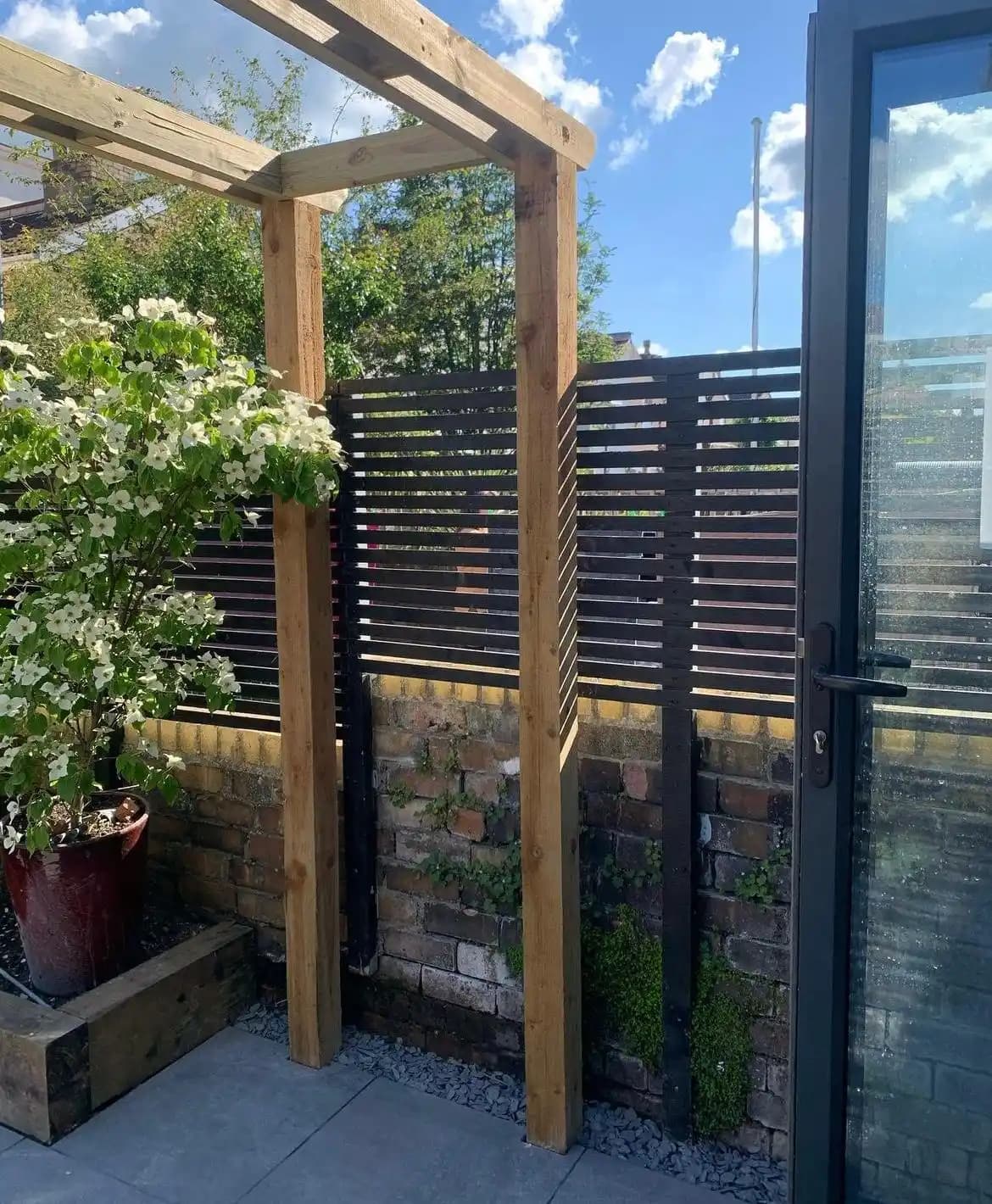 Black horizontal slat screening and timber gate beside a patio