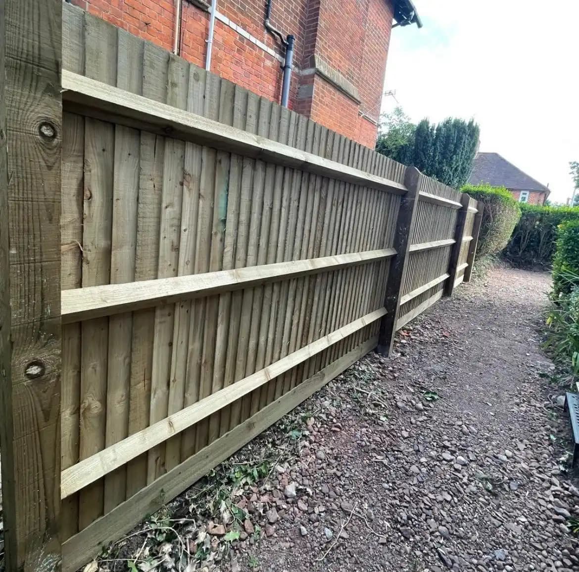 Closeboard fence along the rear of a house beside a gravel path