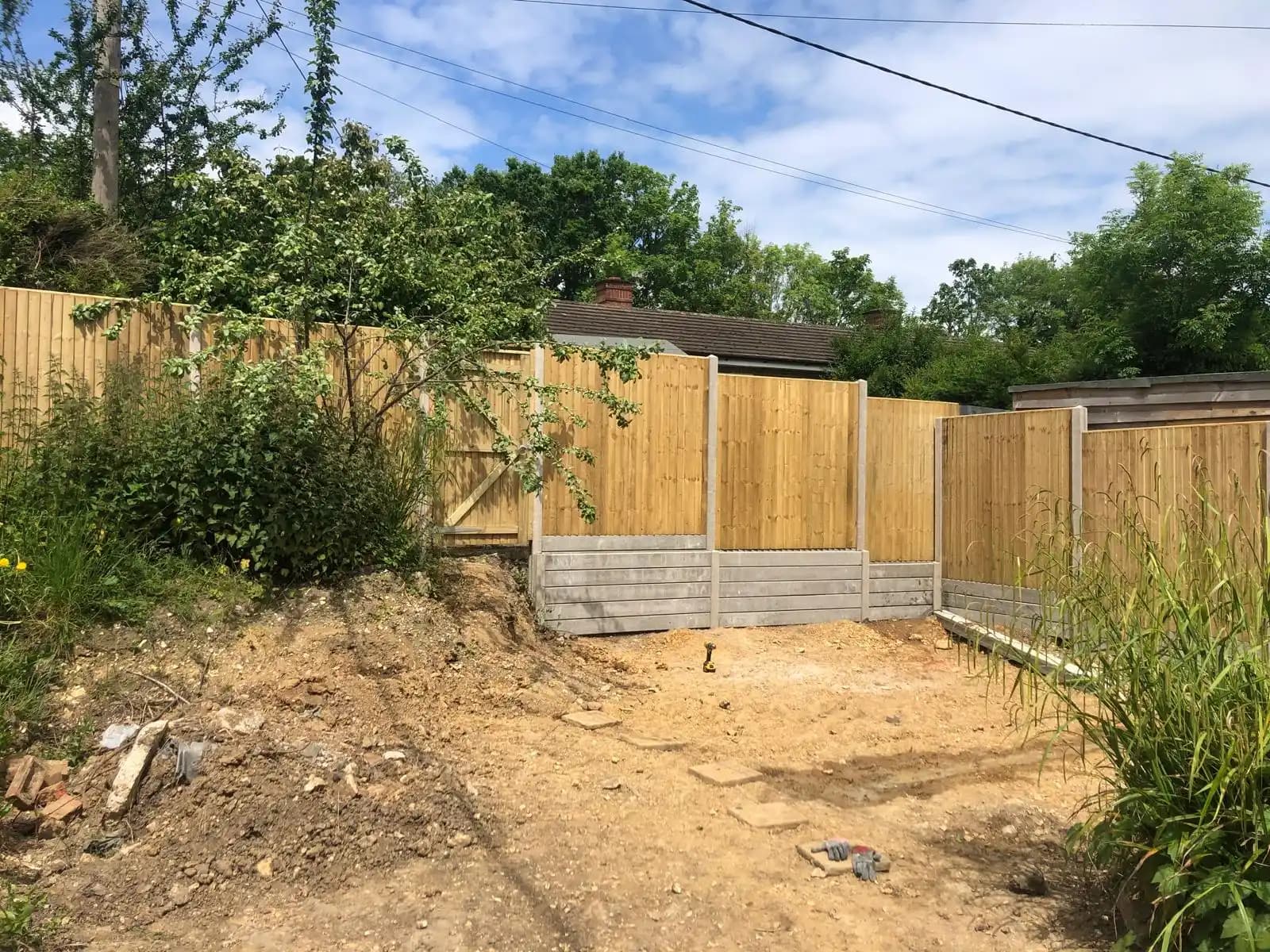 Closeboard fence enclosing a sandy garden corner