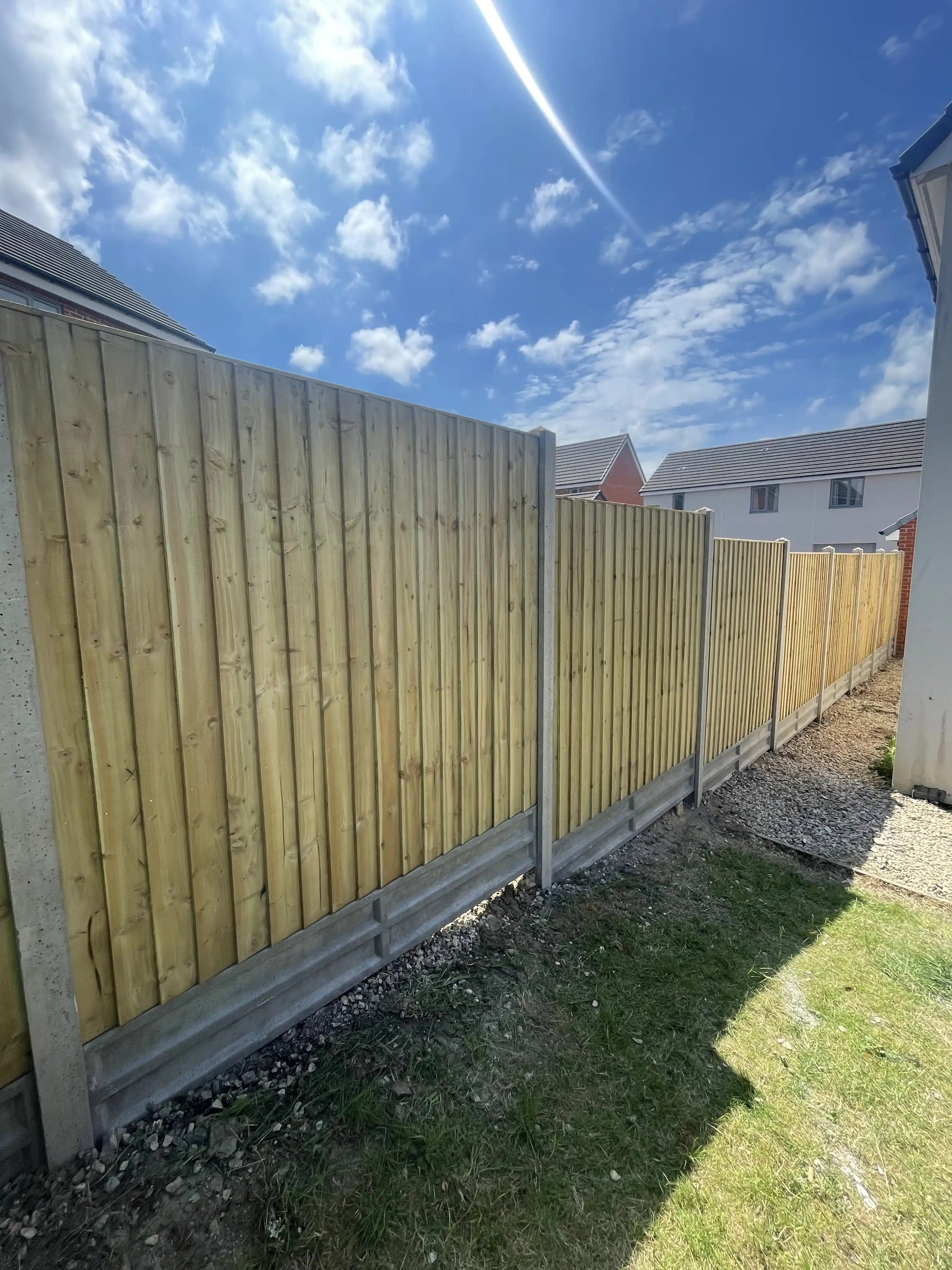 Closeboard fence along a sunny side garden with blue sky