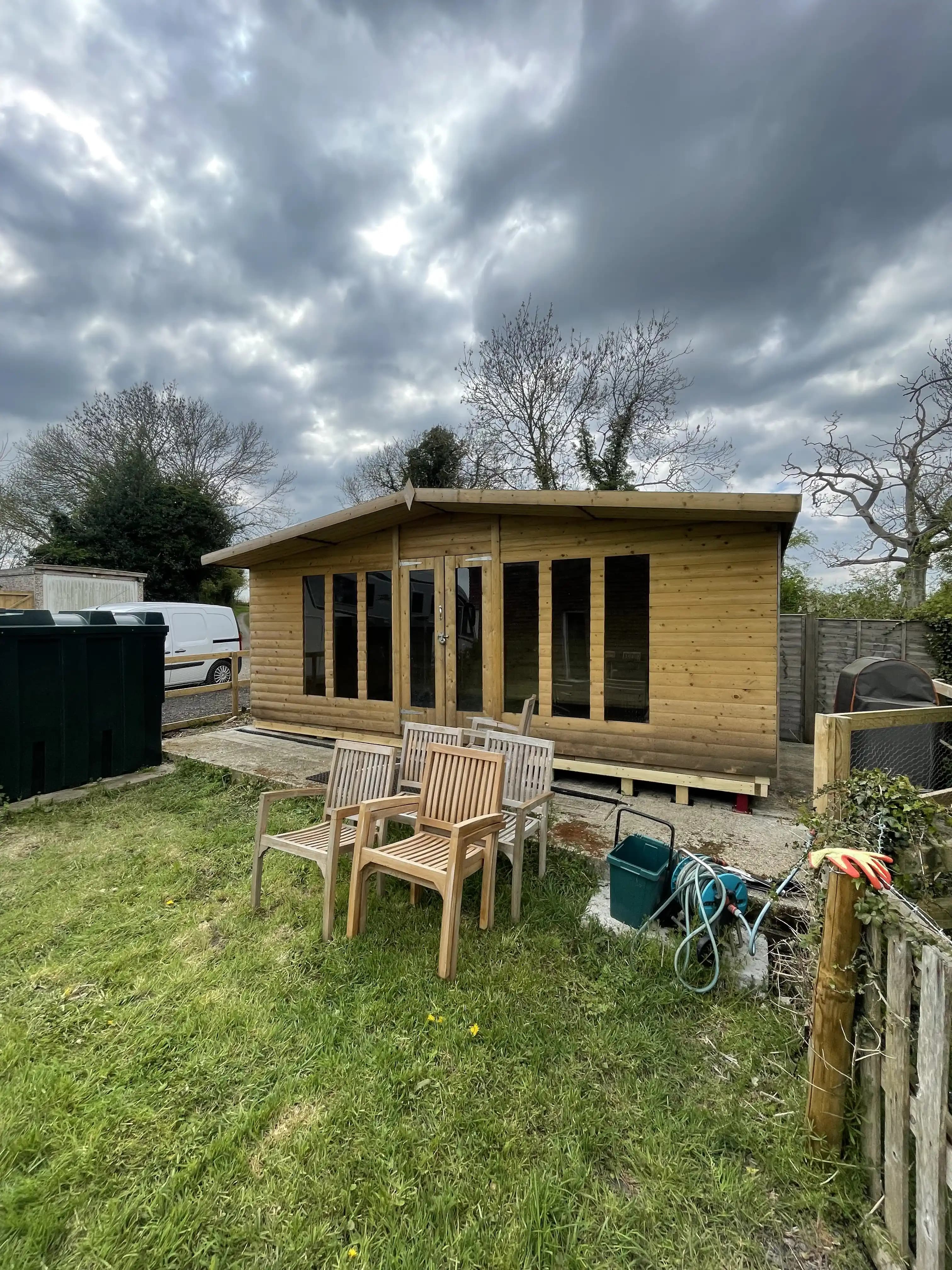 Completed timber garden room facing a lawn and patio furniture