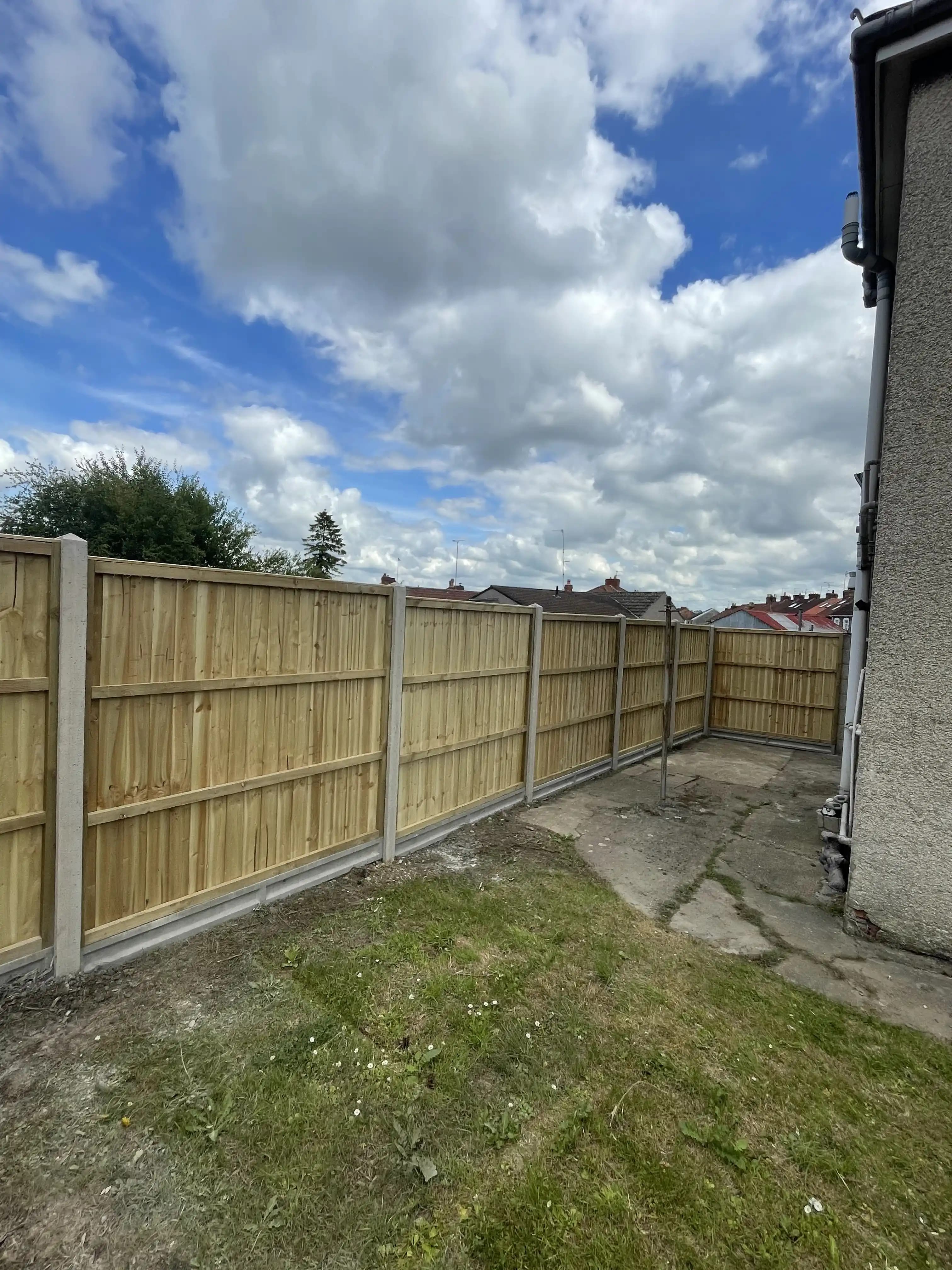 Closeboard fence enclosing a courtyard garden with blue patches in the sky