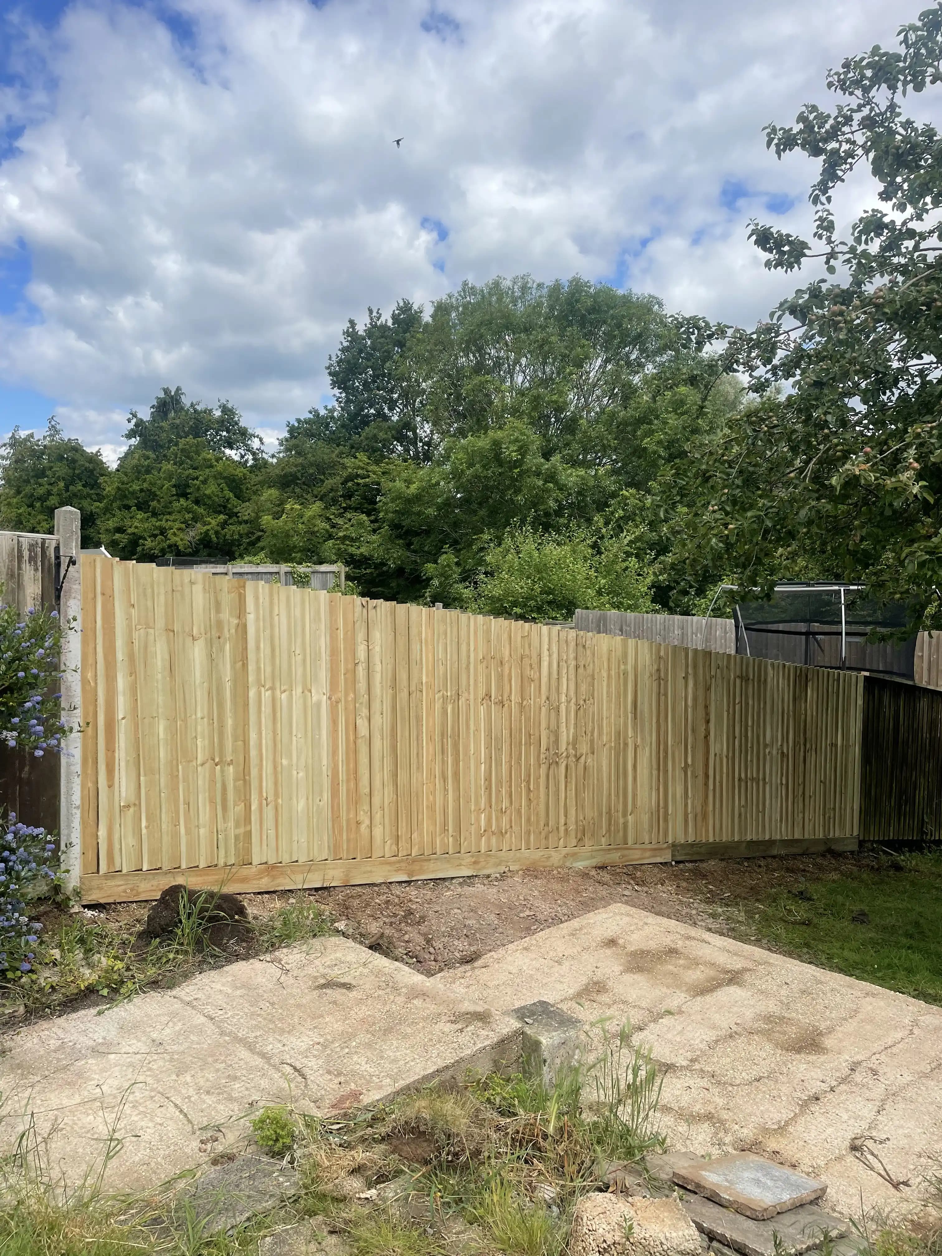 Curved closeboard fence around a paved garden area