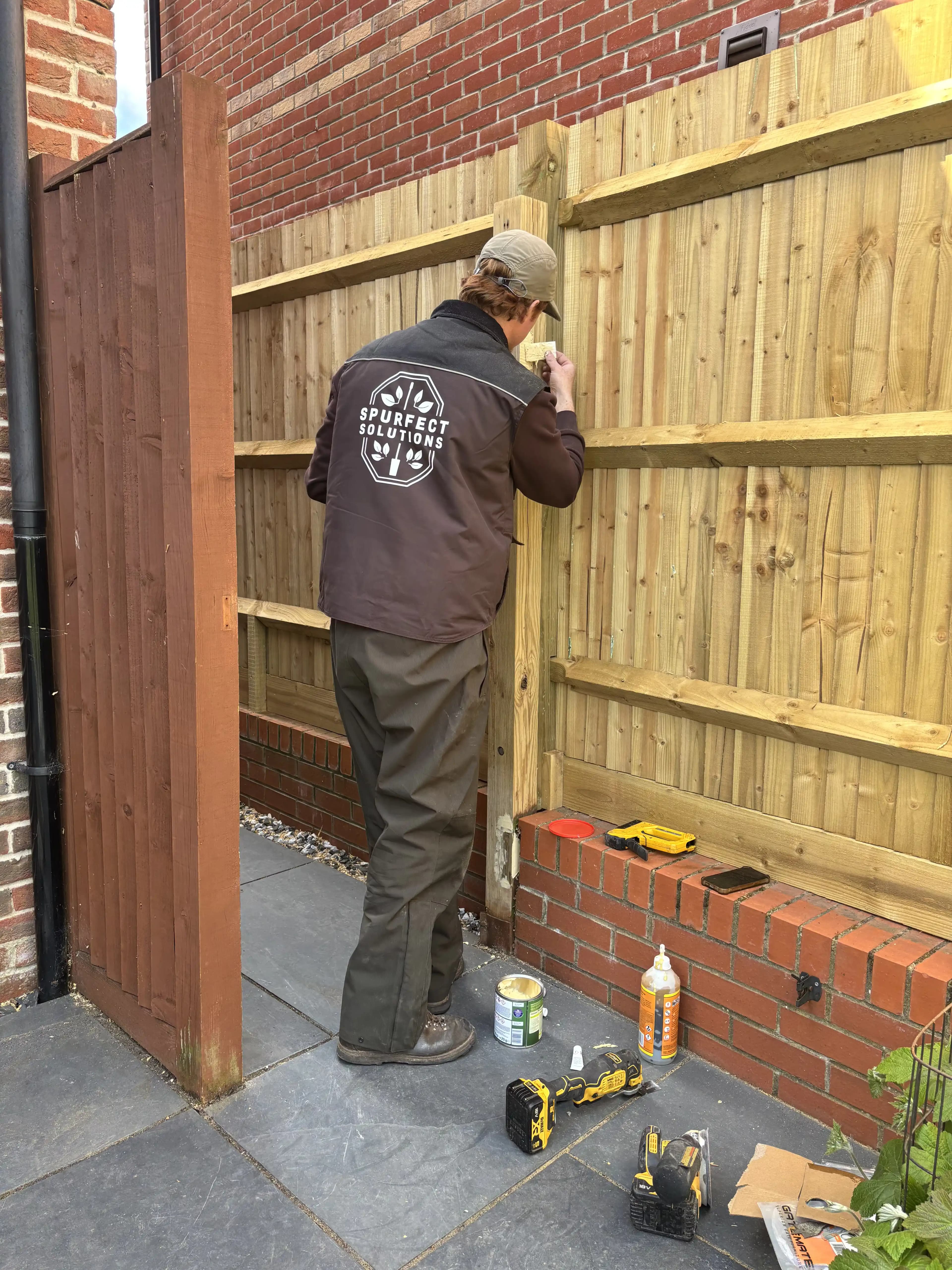 Spurfect installer fitting a timber side gate beside a house