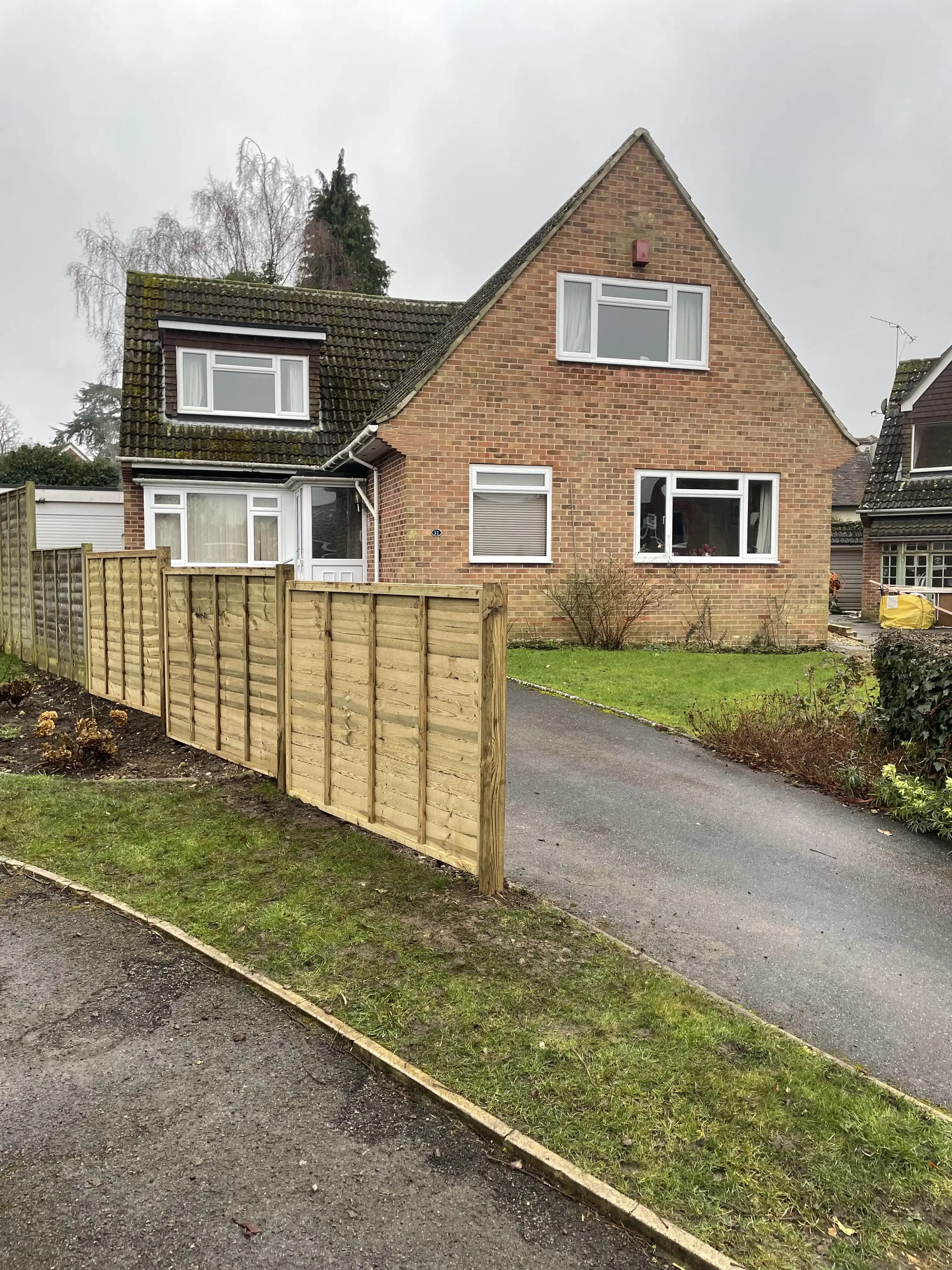 Long timber fence beside a front garden and driveway
