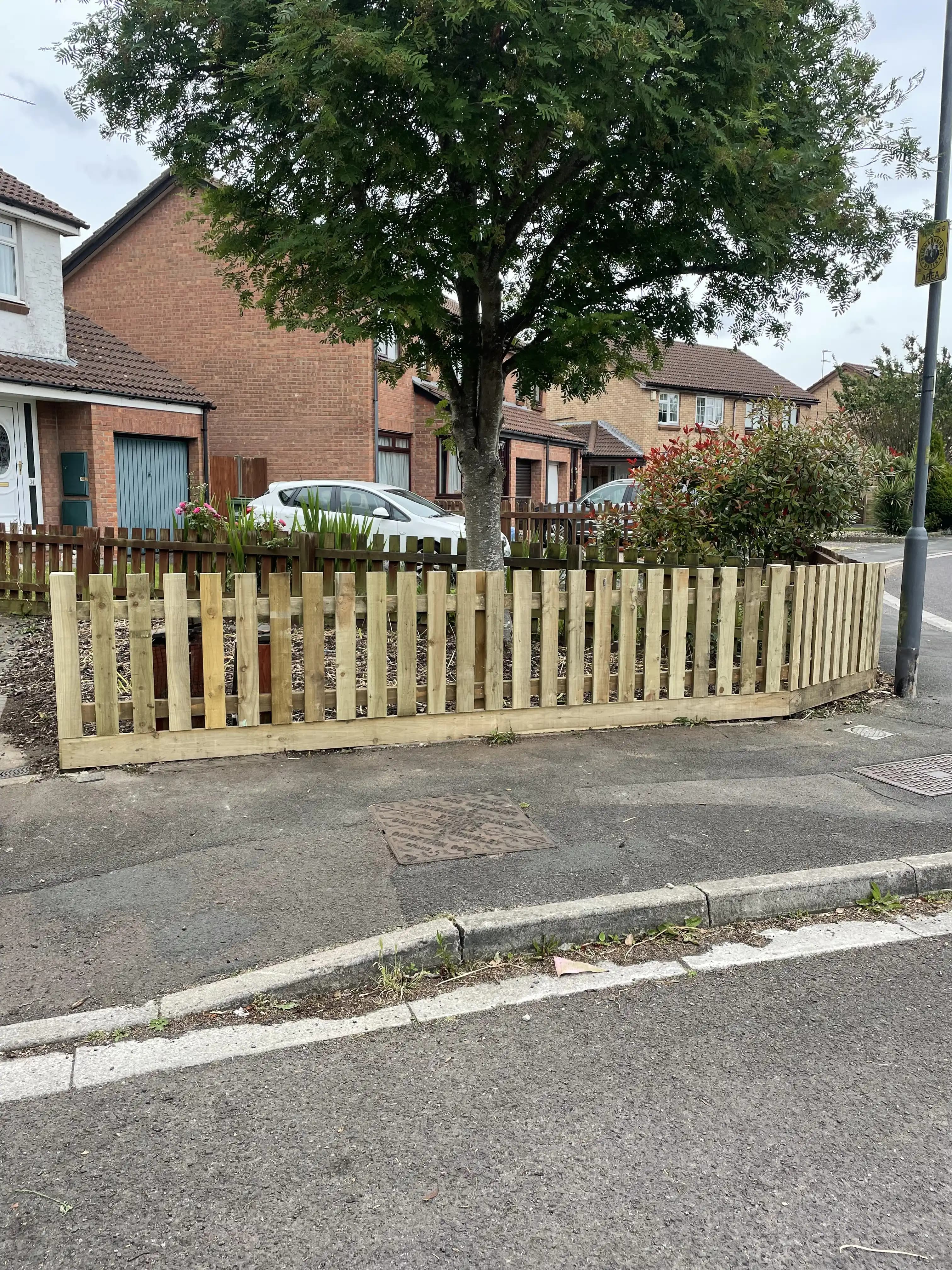 Timber picket fence enclosing a front garden beside the road