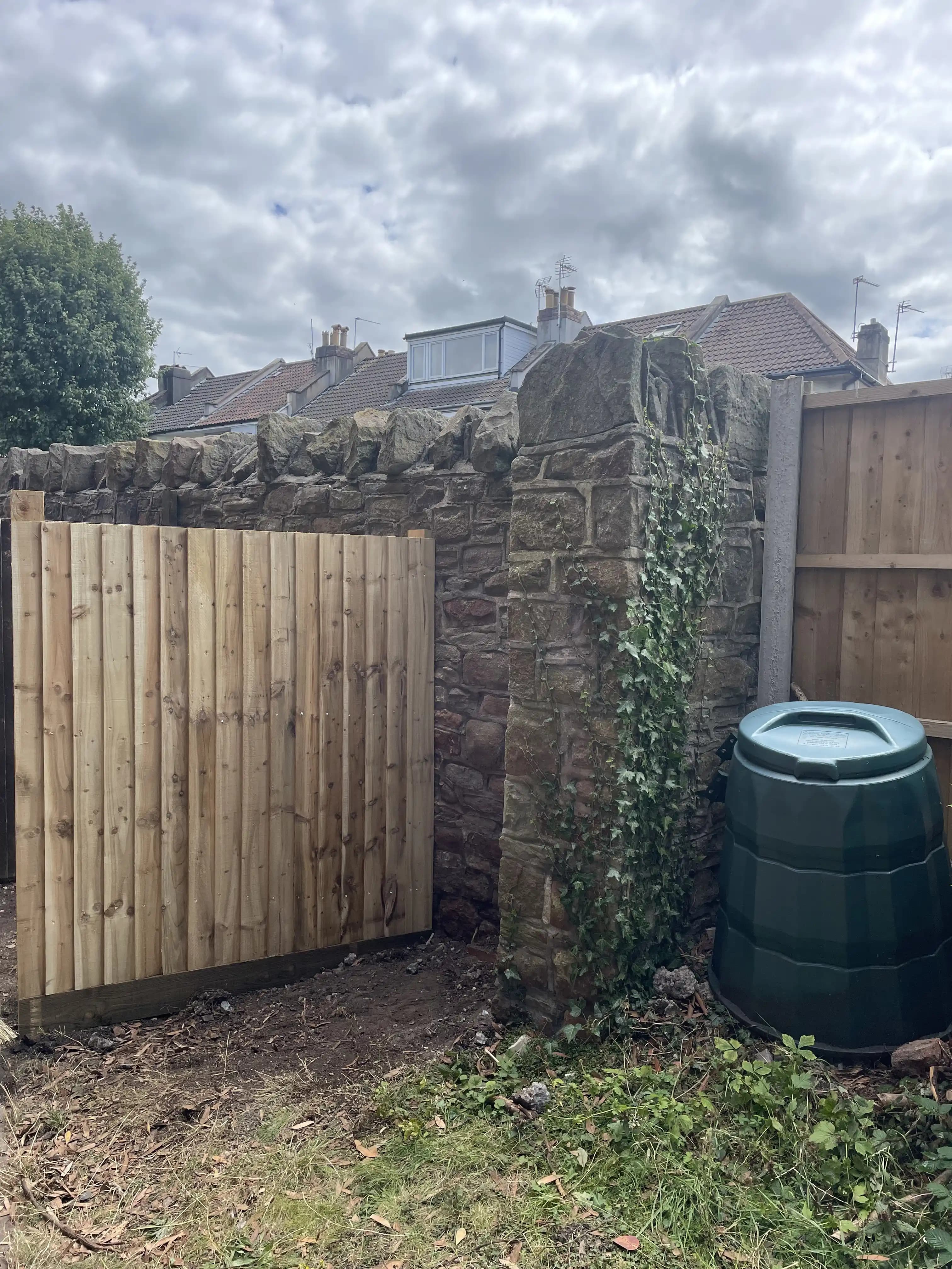 Timber garden gate and fence beside a water butt
