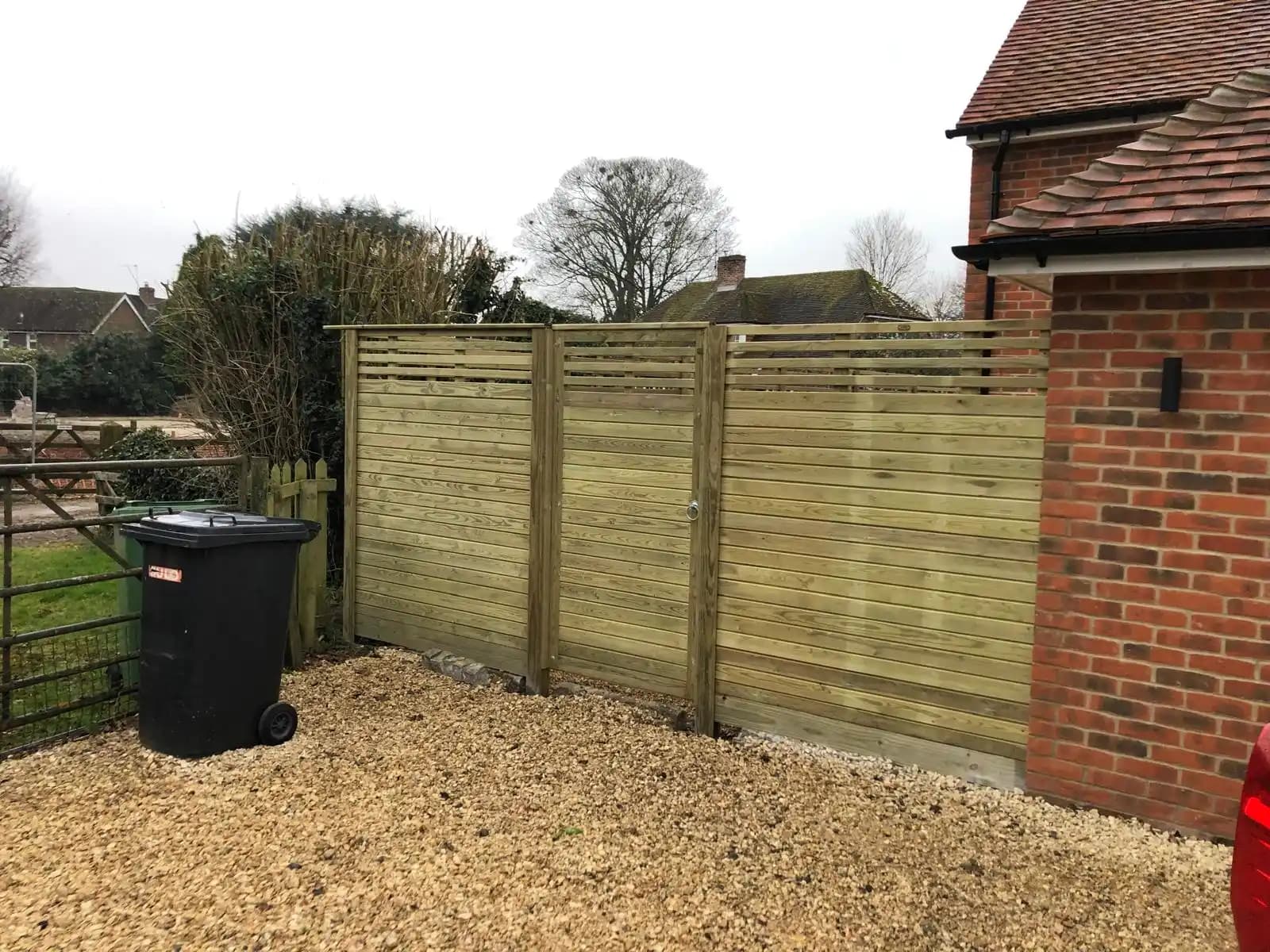 Lap panel fence beside a brick house and gravel area