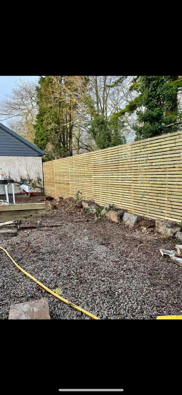 Long closeboard fence along a gravel garden area