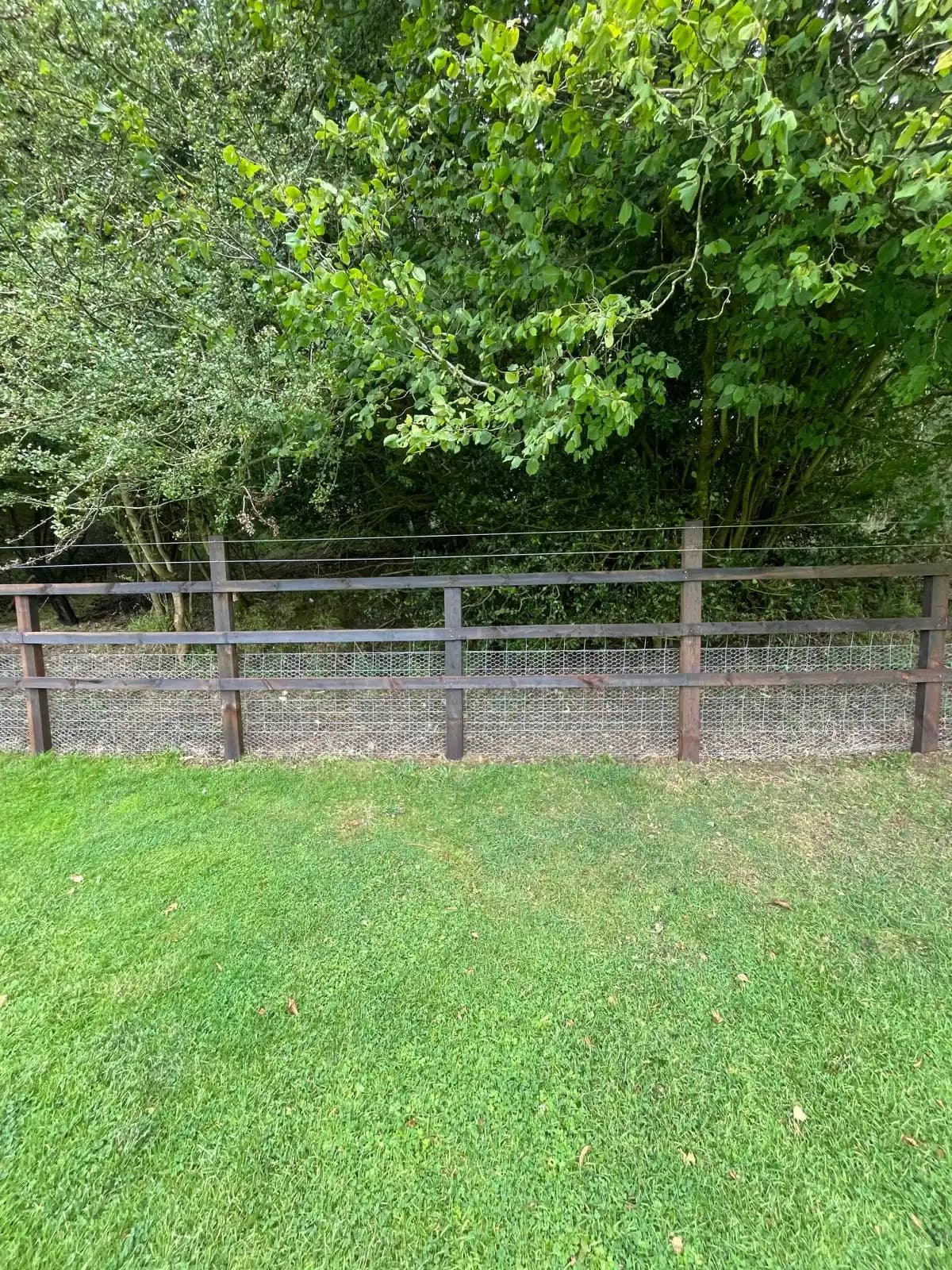 Low post and rail fence bordering a green lawn