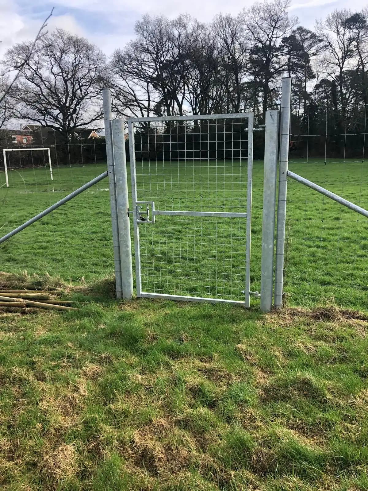 Metal field gate with stock fencing in a grassy field