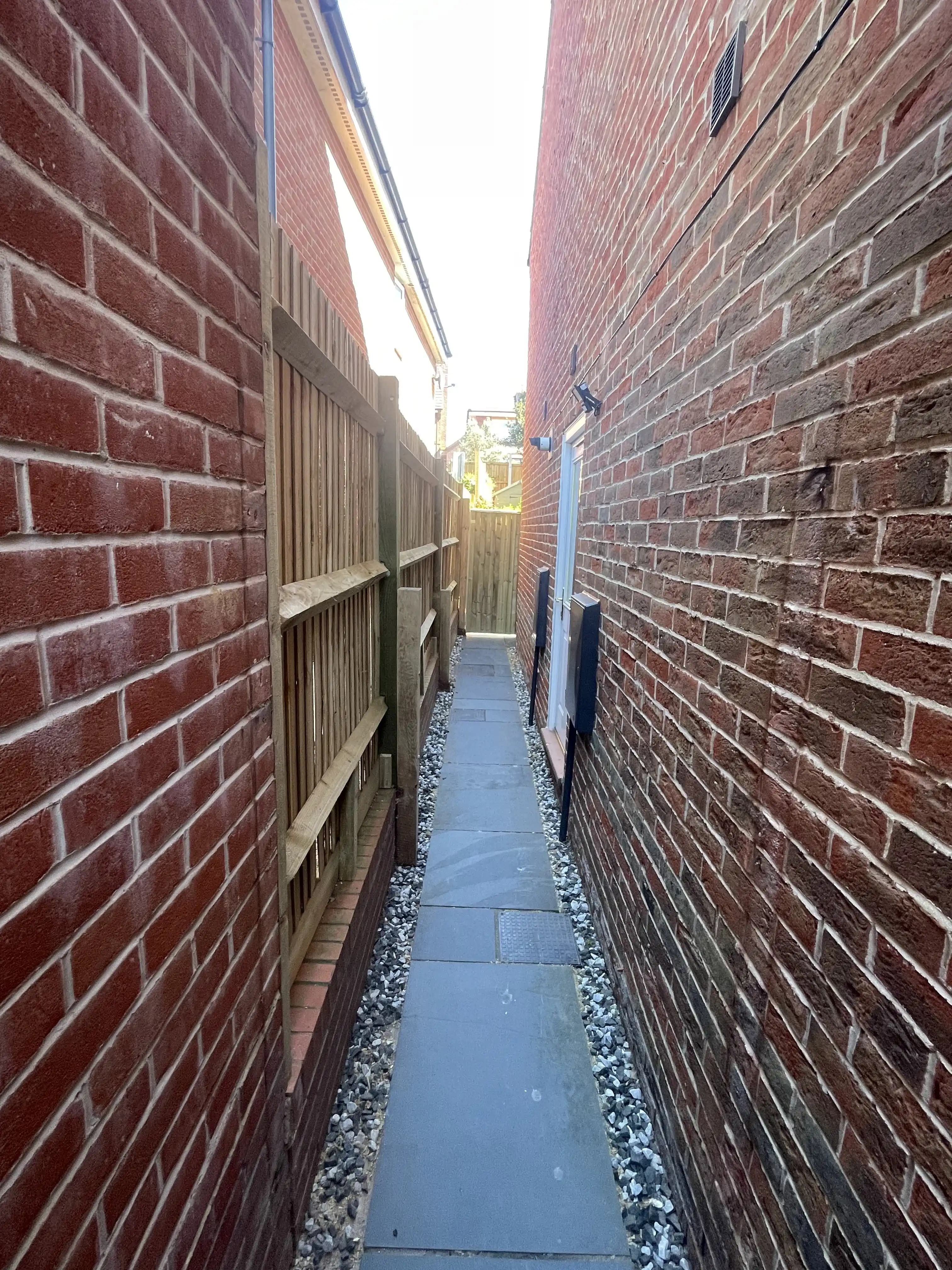 Narrow side return with closeboard fencing along a house wall