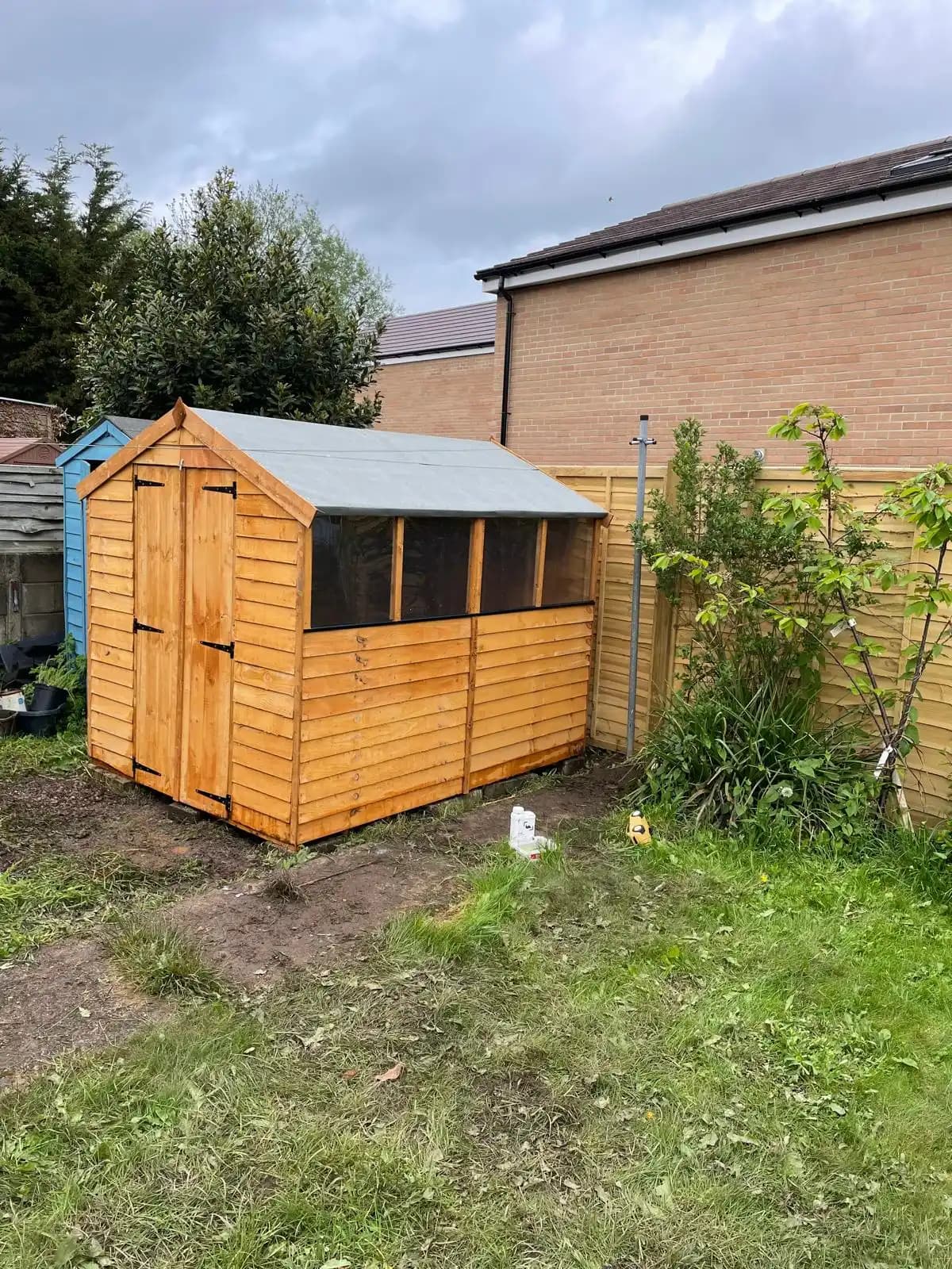 Orange garden shed beside a timber boundary fence