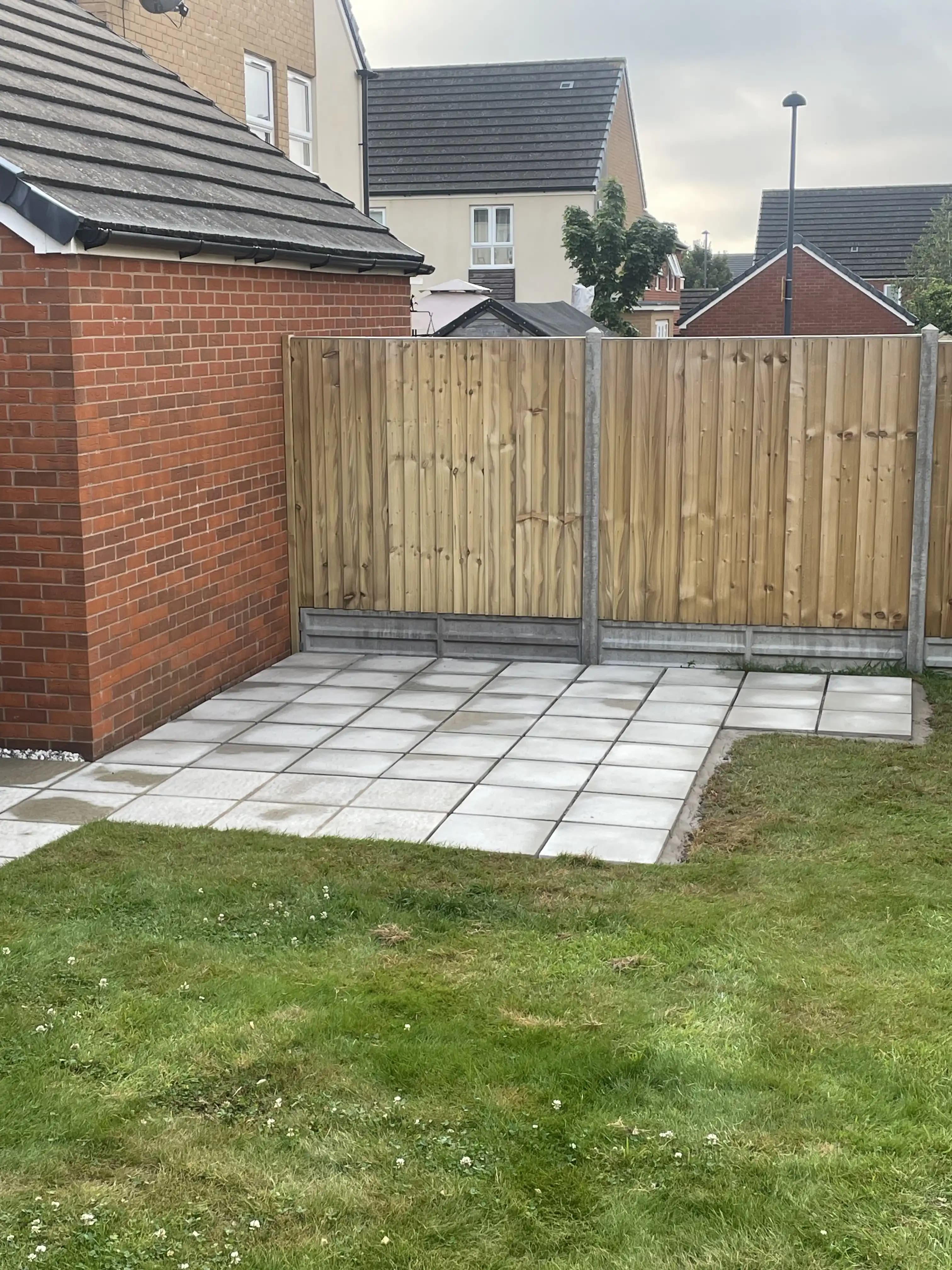 Timber fence panels around a patio beside a red brick house