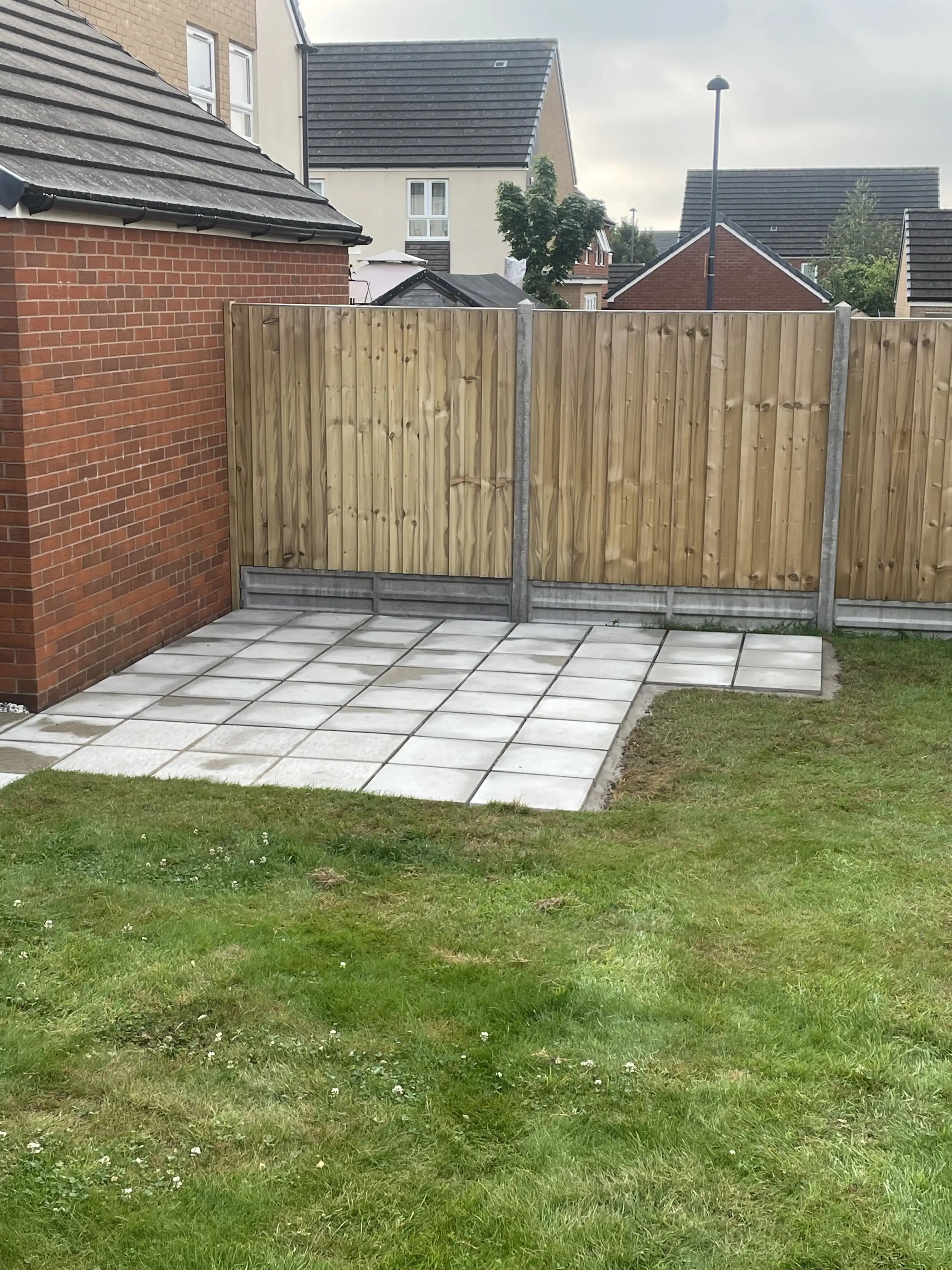 Closeboard fence around a paved patio corner and lawn