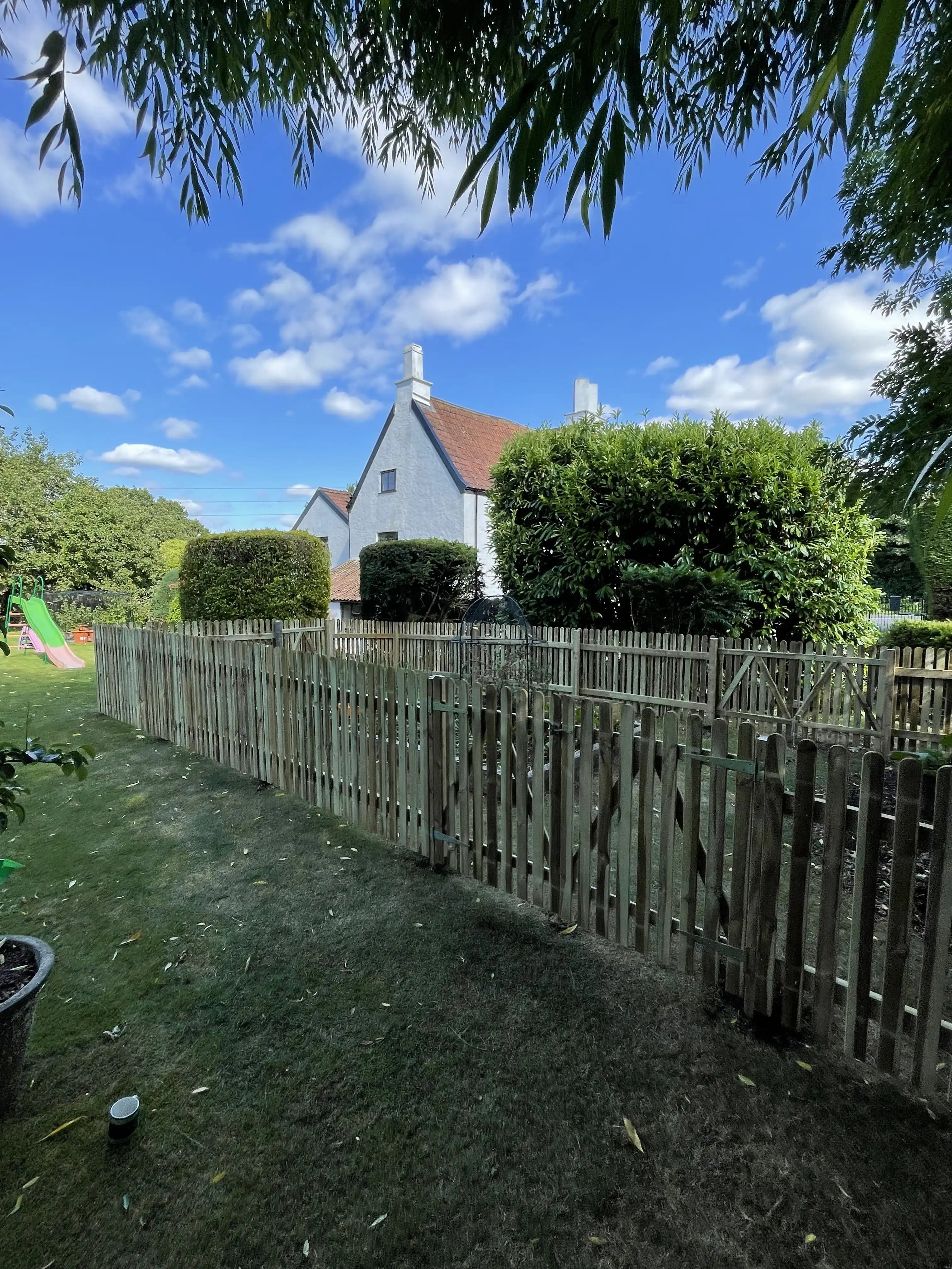 Picket fence marking a garden boundary beneath a blue sky