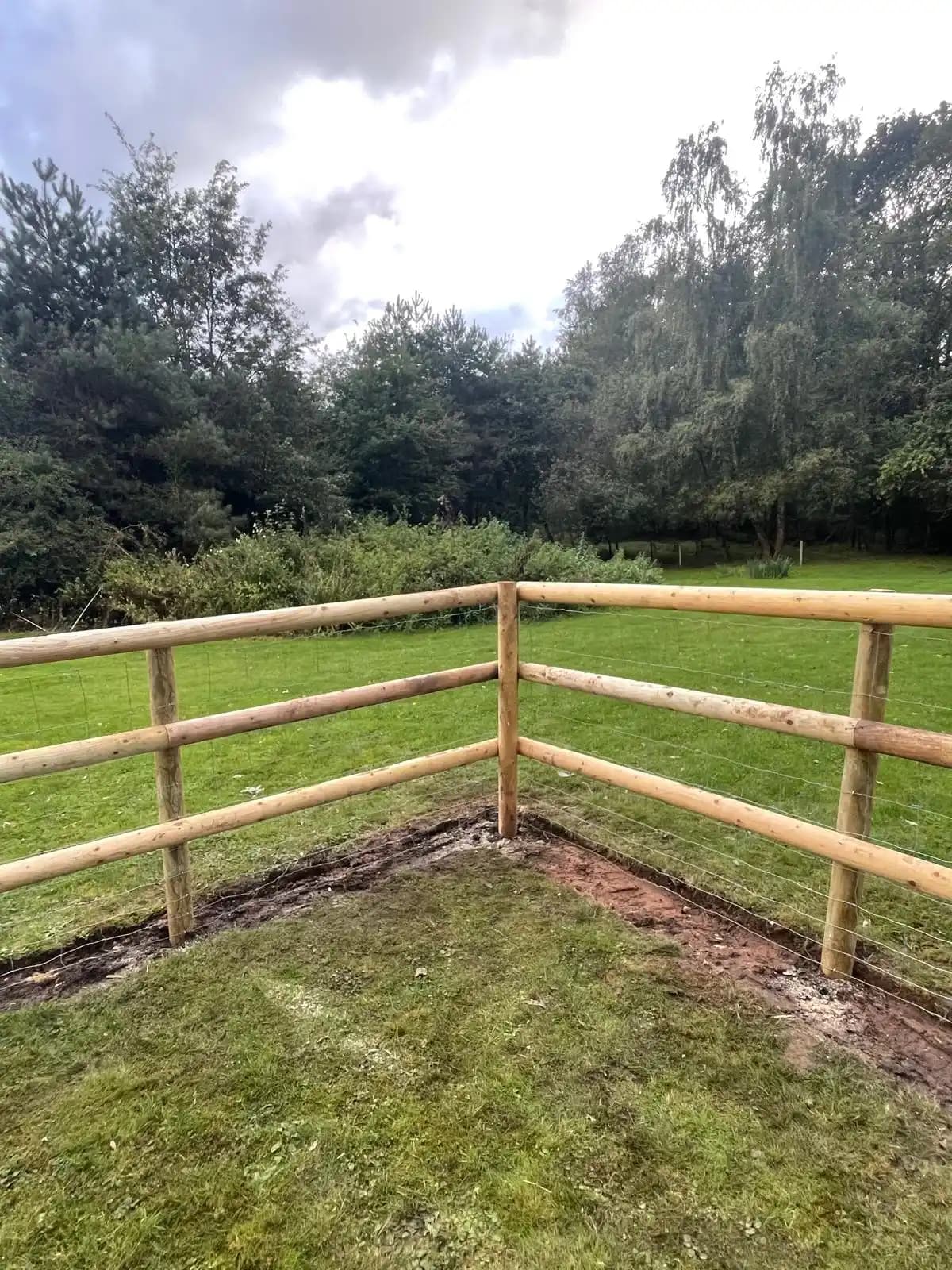 Post and rail corner fence enclosing a garden lawn