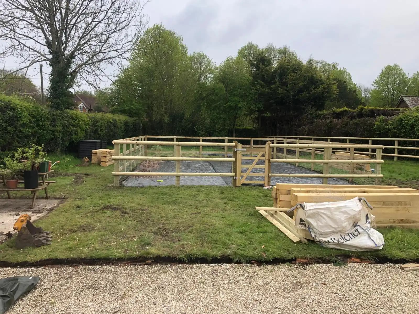 Post and rail fence installation across a garden boundary