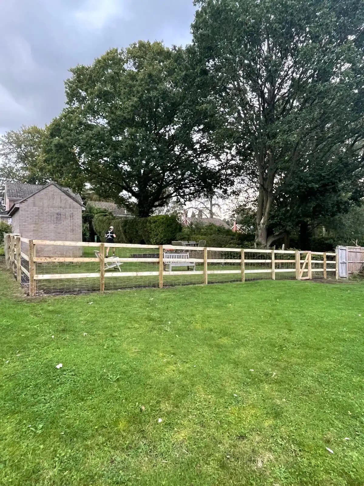 Post and rail field boundary fence across a green lawn