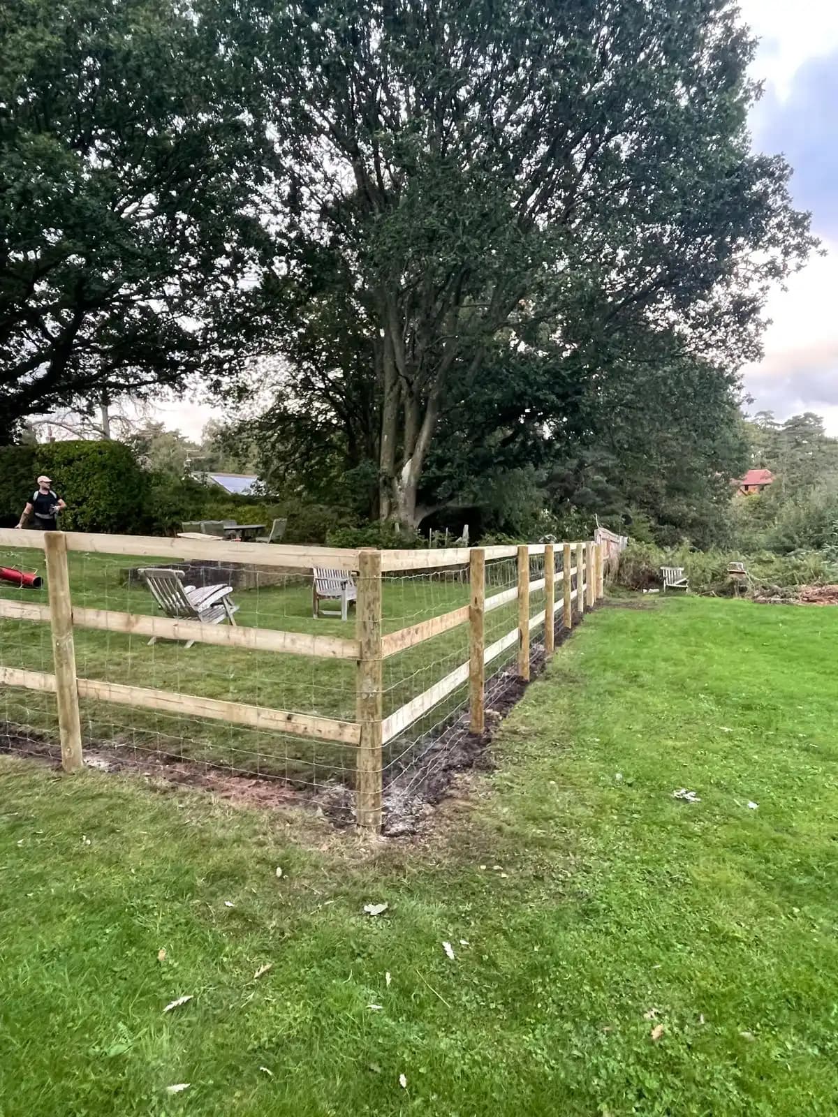 Post and rail garden corner fence beside a mature tree