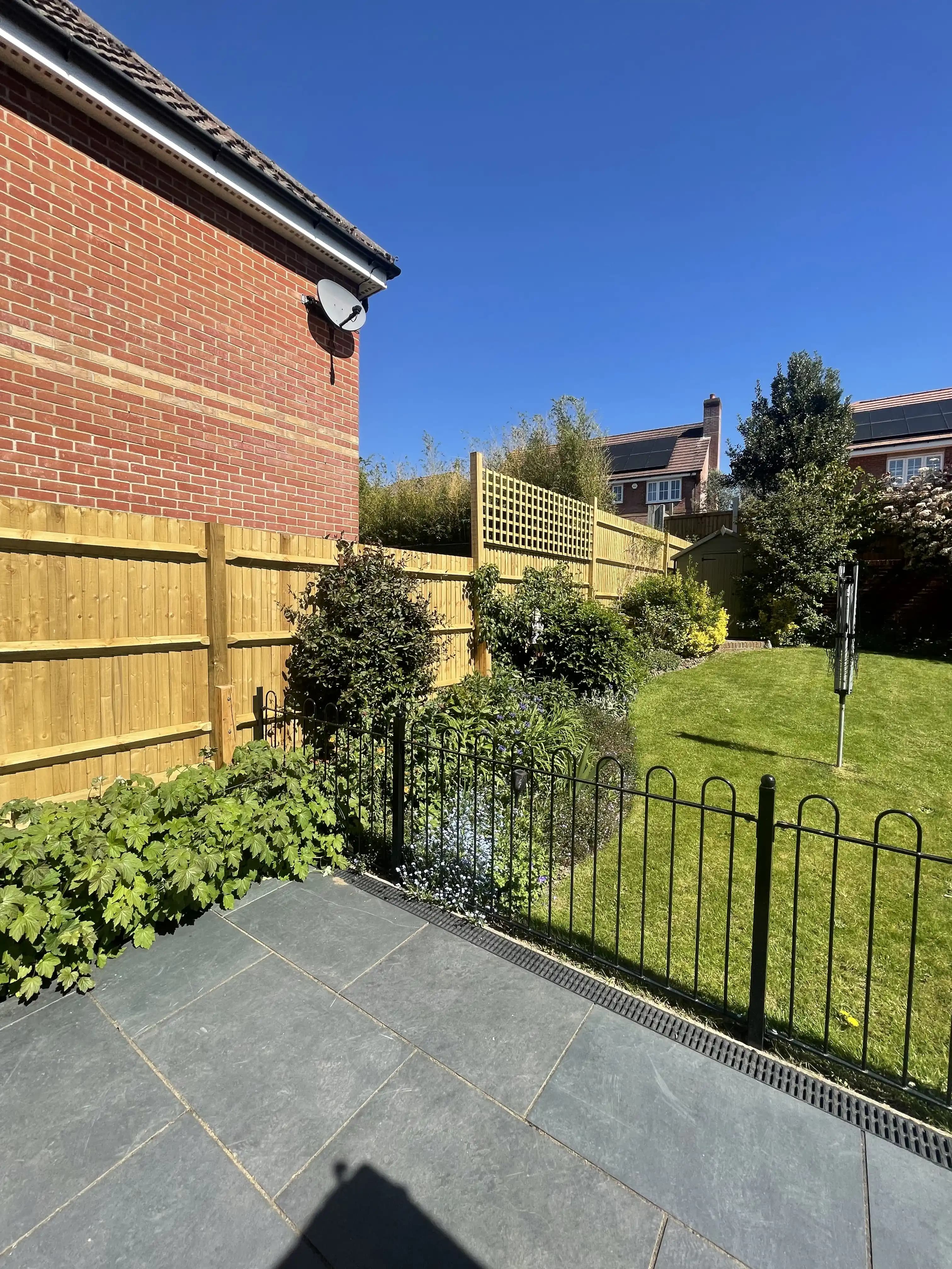 Closeboard fence around a raised patio under a blue sky