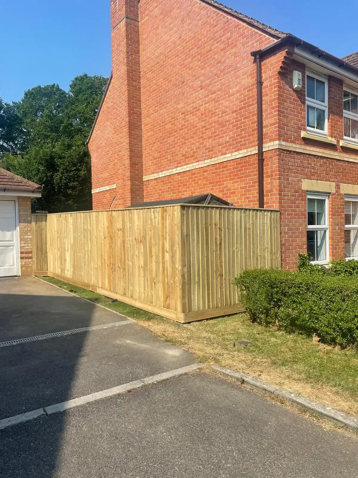 Roadside closeboard fence beside a red brick house