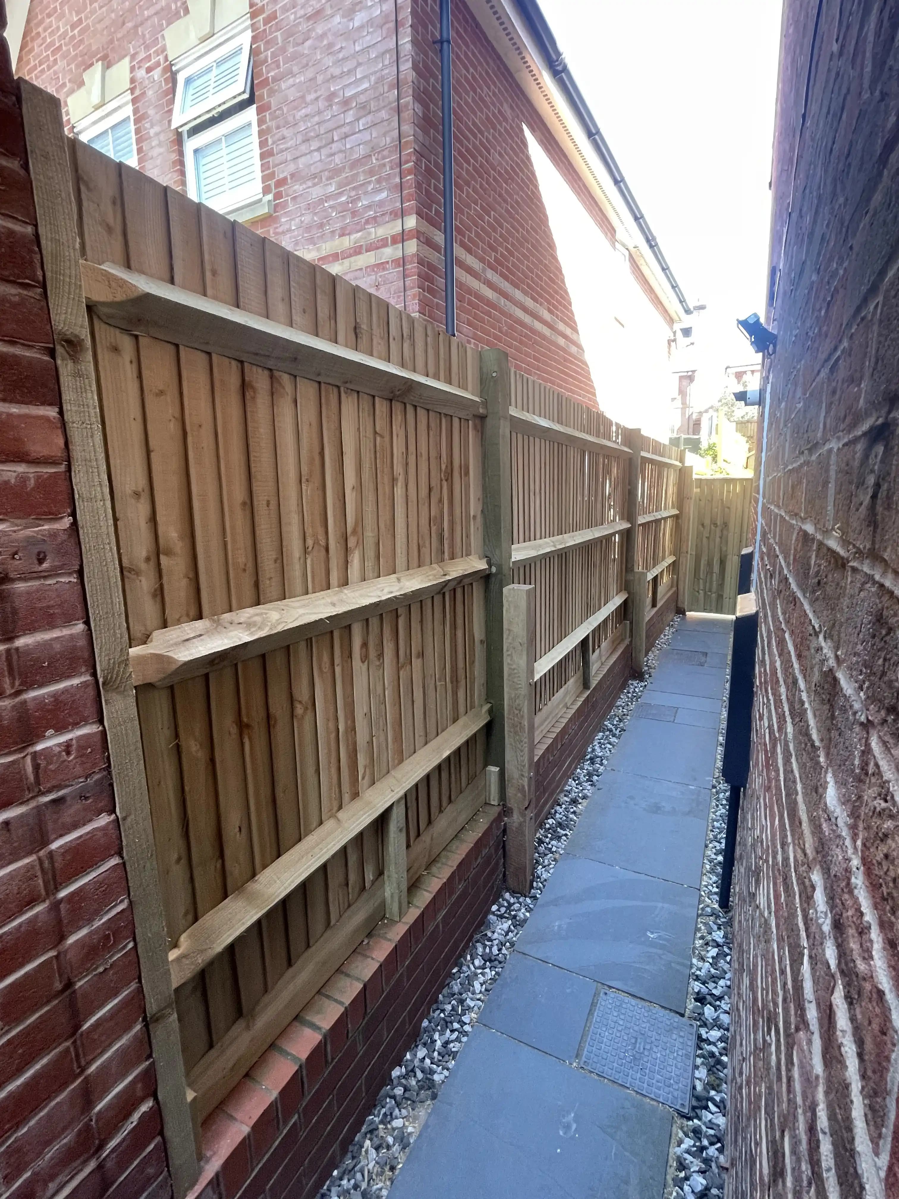 Closeboard fence panels along a narrow side alley