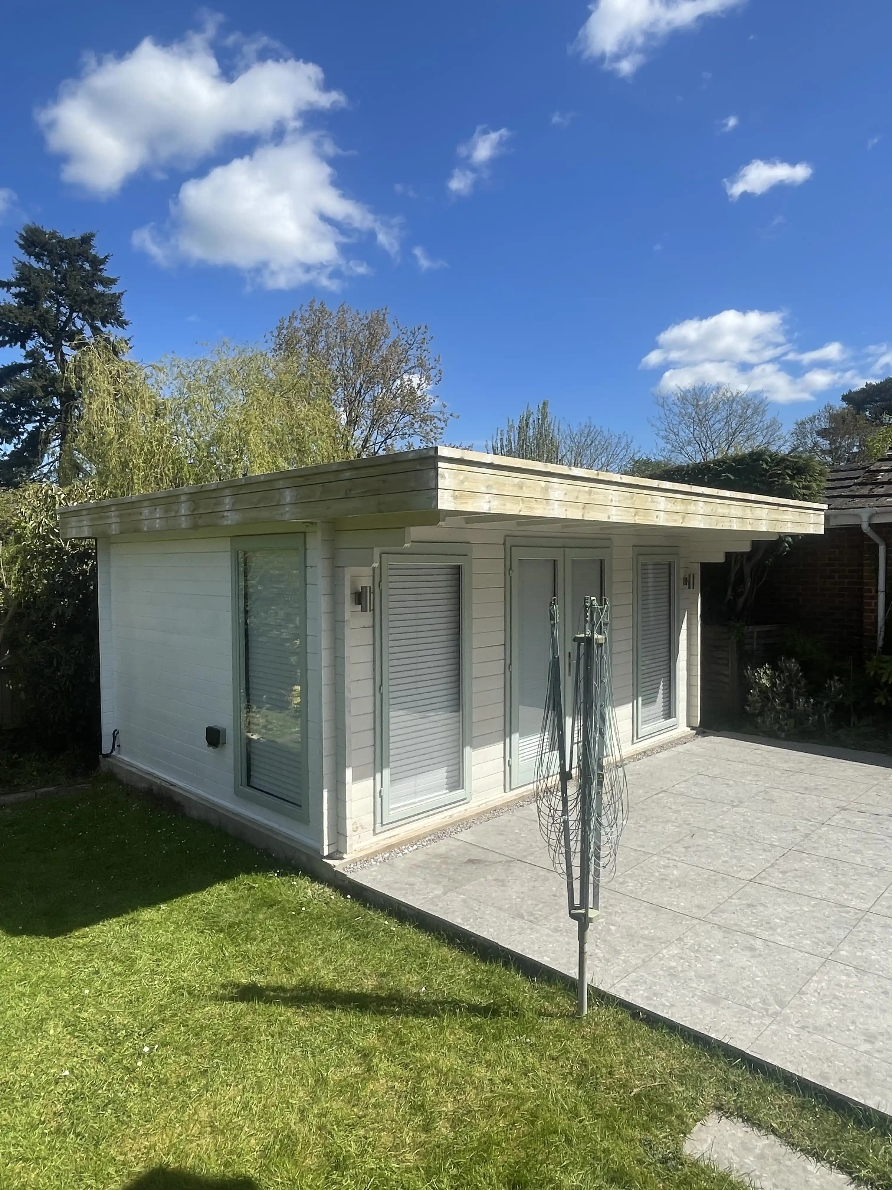 White garden building and patio canopy under a blue sky